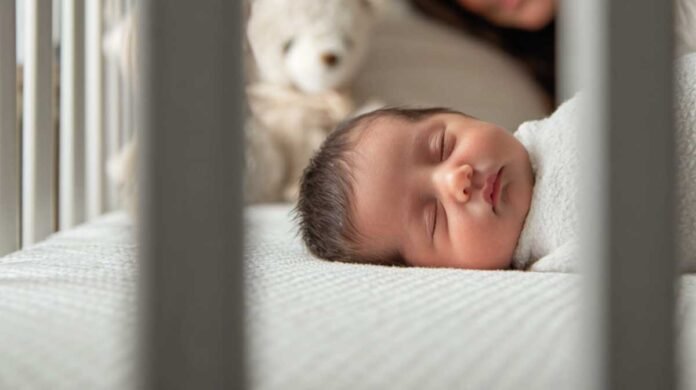 newborn sleeping safely in a crib while a parent watches calmly nearby