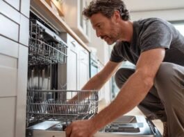 Homeowner installing a dishwasher under a kitchen counter during a DIY installation