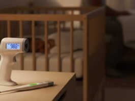 parent holding baby thermometer during calm nighttime newborn check