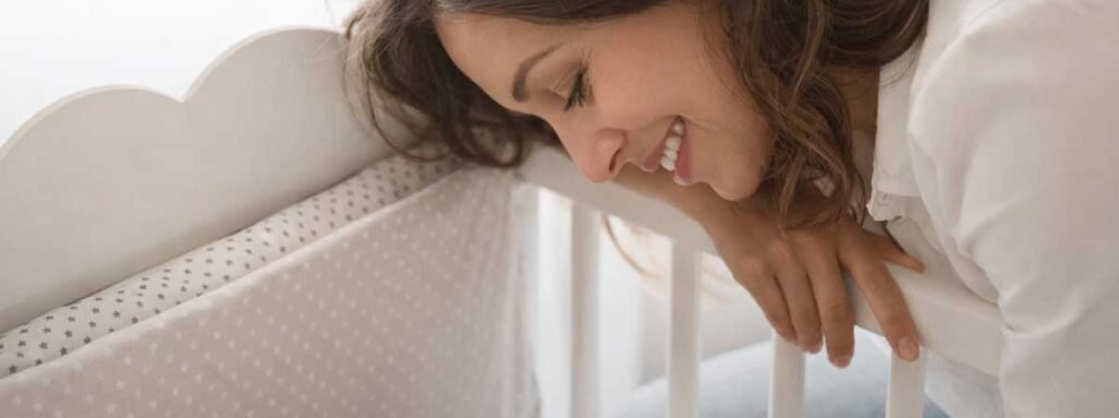 mother gently touching her sleeping newborn in a crib during a calm bedtime moment